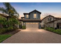 Stunning two-story home featuring a brick driveway, a two-car garage, and mature landscaping at 19563 Roseate Dr, Lutz, FL 33558