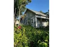 Quaint home with covered porch, partially boarded, surrounded by lush landscaping at 2980 64Th N Ave, St Petersburg, FL 33702