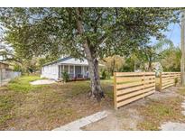 Charming home featuring a covered porch and a natural wood fence, surrounded by mature trees and greenery at 3814 N 48Th St, Tampa, FL 33605