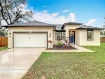 Charming home featuring a two-car garage and a beautifully landscaped front yard and appealing dark trim at 4908 E Hanna Ave, Tampa, FL 33610