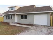 Charming exterior of gray house with a light brown roof and white trim, plus an attached one-car garage at 9062 Sunrise Dr, Largo, FL 33773