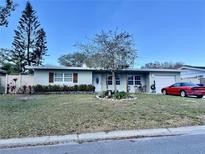 Charming single-story home with a manicured lawn, mature trees, and colorful landscaping at 11248 115Th St, Seminole, FL 33778