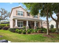 Charming two-story home featuring a stone facade, covered porch with stately columns, and beautifully landscaped front yard at 15912 Ternglade Dr, Lithia, FL 33547