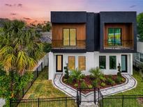 Modern home featuring a black and white facade, balconies, manicured landscaping and a wrought iron fence at 1627 9Th N Ave, St Petersburg, FL 33713