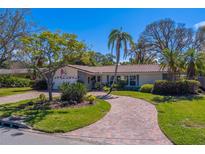 Charming single-story home with brick driveway, mature trees, a tile roof, and a manicured lawn on a sunny day at 809 Royal Dr, Largo, FL 33770