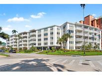 Low-rise apartment building with white facade, balconies, and landscaped grounds on a sunny day at 1100 N Shore Ne Dr # 304, St Petersburg, FL 33701