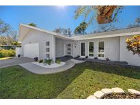 Modern home exterior featuring a well-manicured lawn, walkway, and stylish architectural details including statement windows at 1100 Webb Dr, Clearwater, FL 33755