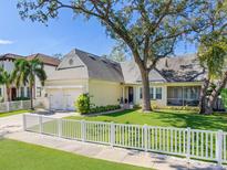 Charming one-story home featuring a white picket fence, and a well-manicured lawn with mature shade trees at 148 Chippewa Ave, Tampa, FL 33606