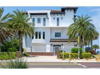 Beautiful three-story home with a red tile roof, white facade, well-manicured landscaping, and wrought iron fencing at 20256 Gulf Blvd, Indian Shores, FL 33785