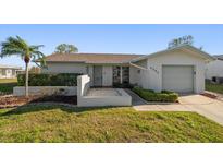 Charming single-story home with a well-manicured lawn, a palm tree, and an attached garage at 4582 Fox Lake Ct, Clearwater, FL 33762