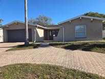 Charming single-story home with brick driveway, attached garage, and inviting entryway beneath a clear blue sky at 8615 Newton Dr, Port Richey, FL 34668