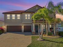Two-story home boasting a tile roof, lush landscaping, three-car garage, and inviting curb appeal at 11965 Cinnamon Fern Dr, Riverview, FL 33579