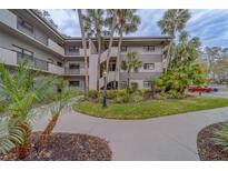 Condominium building's exterior features lush tropical landscaping and multiple levels of balconies with metal railings at 2650 Countryside Blvd # F209, Clearwater, FL 33761