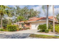 Charming home exterior with a tile roof, lush landscaping, and a two-car garage at 4579 Del Sol S Blvd, Sarasota, FL 34243