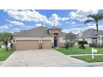 Charming home with a well-manicured lawn, lush landscaping, and a spacious three-car garage at 4644 Braesgate Ct, Land O Lakes, FL 34639