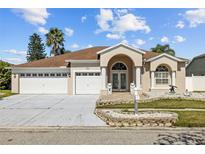 Home with a two-car garage, manicured landscaping, and double door entrance framed by stately columns at 5117 Spectacular Bid Dr, Wesley Chapel, FL 33544