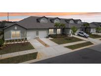Charming townhome exterior featuring a two-car garage, well-maintained lawn and beautiful landscaping at 6850 Ripple Pond Loop, Zephyrhills, FL 33541
