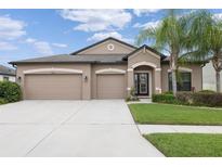 Charming home showcasing a well-manicured lawn and a three-car garage in a serene neighborhood at 18620 Cortes Creek Blvd, Spring Hill, FL 34610