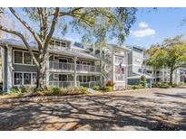 Condominium complex with multiple floors, white railings, and a well-maintained landscaped yard at 2511 Dolly Bay Dr # 304, Palm Harbor, FL 34684