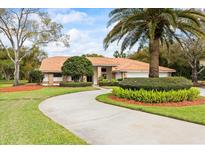 Single-story home with a circular driveway, tile roof, lush landscaping, and a welcoming entrance at 30 Stanton Cir, Oldsmar, FL 34677