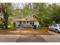 Charming single-story home featuring a yellow front door, mature trees, and an unfenced front yard at 3425 E Powhatan Ave, Tampa, FL 33610