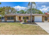 Charming single-story home boasting a stone facade, manicured lawn, and a convenient attached garage at 834 Riverside Dr, Tarpon Springs, FL 34689