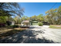 Wide driveway leading to a one-story home with an attached garage and large green lawn at 9377 Preston Rd, Brooksville, FL 34601