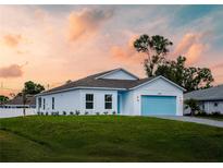 Charming single-story home featuring a blue garage door, a well-manicured lawn, and a serene neighborhood setting at 22442 Peachland Blvd, Port Charlotte, FL 33954