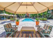 Relaxing community pool area featuring lounge chairs and cabanas for shade on a sunny day at 2402 W Azeele St # 423, Tampa, FL 33609