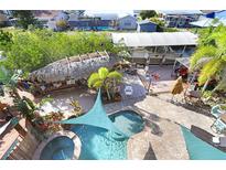 An aerial view of a backyard with a pool, tiki hut, and boat dock, perfect for waterfront living at 541 Treviso Dr, Apollo Beach, FL 33572