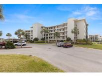 Condo building exterior with parking lot and palm trees on a sunny day at 8141 Aquila St # 322, Port Richey, FL 34668