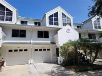Attractive two-story townhouse featuring a white exterior, attached garage and manicured landscaping at 9914 Indian Key Trl # 32, Seminole, FL 33776