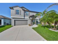 Two-story home featuring a gray exterior, manicured lawn, and a two-car garage at 10112 Rose Petal Pl, Riverview, FL 33578
