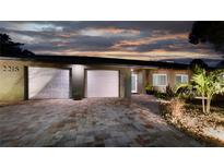 Charming home featuring a well-manicured front yard and a brick driveway leading to a two-car garage, shot at twilight at 2215 River Ridge Dr, Sarasota, FL 34239