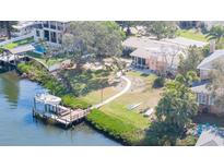 Waterfront property featuring a private dock, lush landscaping, and screened-in porch overlooking the tranquil canal at 4907 W Spring Lake Dr, Tampa, FL 33629