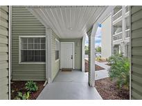 Inviting entrance with sage green siding, decorative columns, and a neutral-colored walkway at 6916 Stones Throw N Cir # 9110, St Petersburg, FL 33710