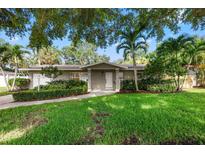 Charming single-story home featuring lush landscaping, a well-manicured lawn, and a welcoming front entrance at 1180 Eden Isle Ne Blvd, St Petersburg, FL 33704