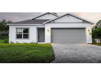 Charming one-story home with a gray brick driveway, an attached two car garage, and manicured lawn at 134 Jade St, Rotonda West, FL 33947