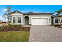 Charming single Gathering home with a light green exterior and a well-maintained paver driveway at 17069 Moonflower Dr, Venice, FL 34293