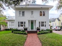 Charming two-story home featuring a landscaped yard, brick walkway, and green front door at 2514 W Morrison Ave, Tampa, FL 33629