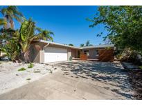 Charming single-story home featuring an attached garage, front deck, and tropical landscaping at 305 160Th Ter, Redington Beach, FL 33708