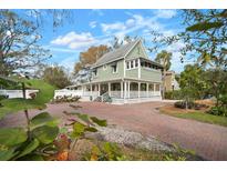 Charming two-story home with a wrap-around porch and beautiful landscaping and circular brick driveway at 6835 S Shamrock St, Tampa, FL 33616
