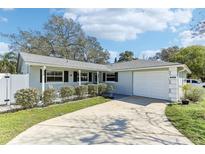 Charming single-story home with a well-manicured lawn and a concrete driveway leading to an attached garage at 1015 Coldstream Ct, Tarpon Springs, FL 34689