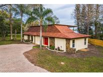 Charming home with a unique roof, stone accents, and a circular brick driveway at 14333 Lake Magdalene Blvd, Tampa, FL 33618