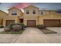 Inviting exterior view of the townhome featuring a two-car garage, well-maintained landscaping, and a neutral color palette at 2007 Hawks View Dr, Ruskin, FL 33570