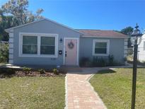 Charming single-story home with a brick walkway, pink door, and manicured front lawn at 2235 20Th St S, St Petersburg, FL 33712