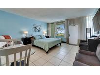 Bright bedroom features light blue walls, tile floor, queen bed, beach decor and a window overlooking a green field at 611 Destiny Dr # 304, Ruskin, FL 33570