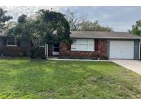 Charming single story home with brick facade, red shutters, and a well-maintained lawn at 16240 Lake Palm Dr, Lutz, FL 33549