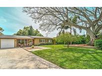 Charming single-story home with a well-manicured lawn, paver walkway, and mature shade trees at 202 Dunkirk Rd, Oldsmar, FL 34677