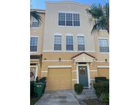 Townhouse exterior with a one-car garage, teal entry door and well manicured landscaping at 3128 Bayshore Oaks Dr, Tampa, FL 33611